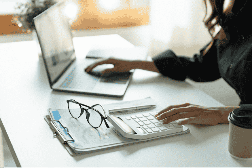 Auto-entrepreneuse calculant ses finances professionnelles sur ordinateur et calculatrice
