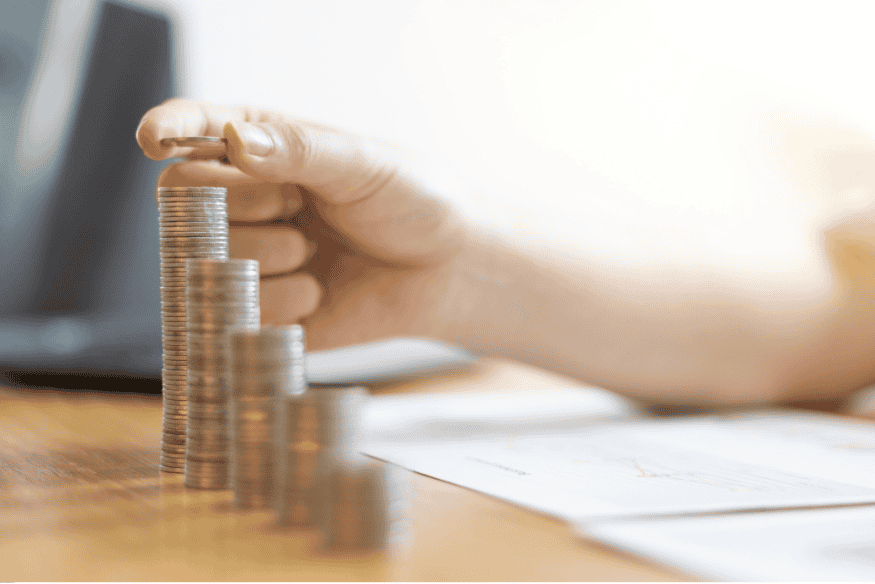 Main empilant des pièces de monnaie sur un bureau pour illustrer la gestion rigoureuse des finances