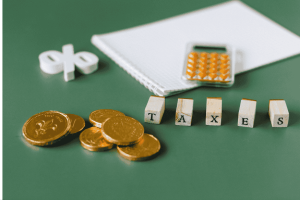 Bloc de pièces, calculatrice et lettres formant le mot TAXES sur fond vert