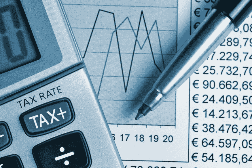 Calendrier fiscal avec billets en euros, horloge et mot TAX en lettres de bois