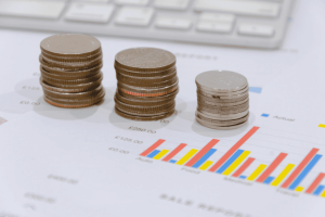 Piles de pièces placées sur un rapport de ventes avec graphiques, représentant la croissance financière.
