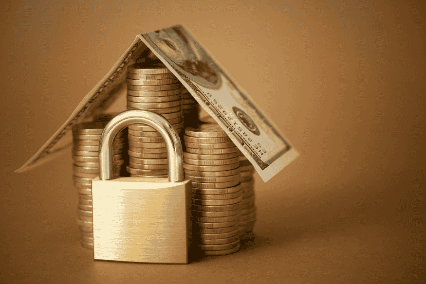 Cadenas doré protégeant des piles de pièces et de billets, symbolisant la sécurité des actifs financiers.