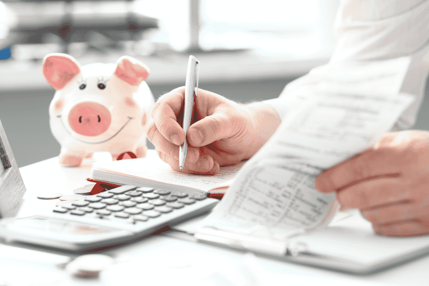 Entrepreneur examinant des reçus et des factures avec calculatrice et tirelire sur le bureau